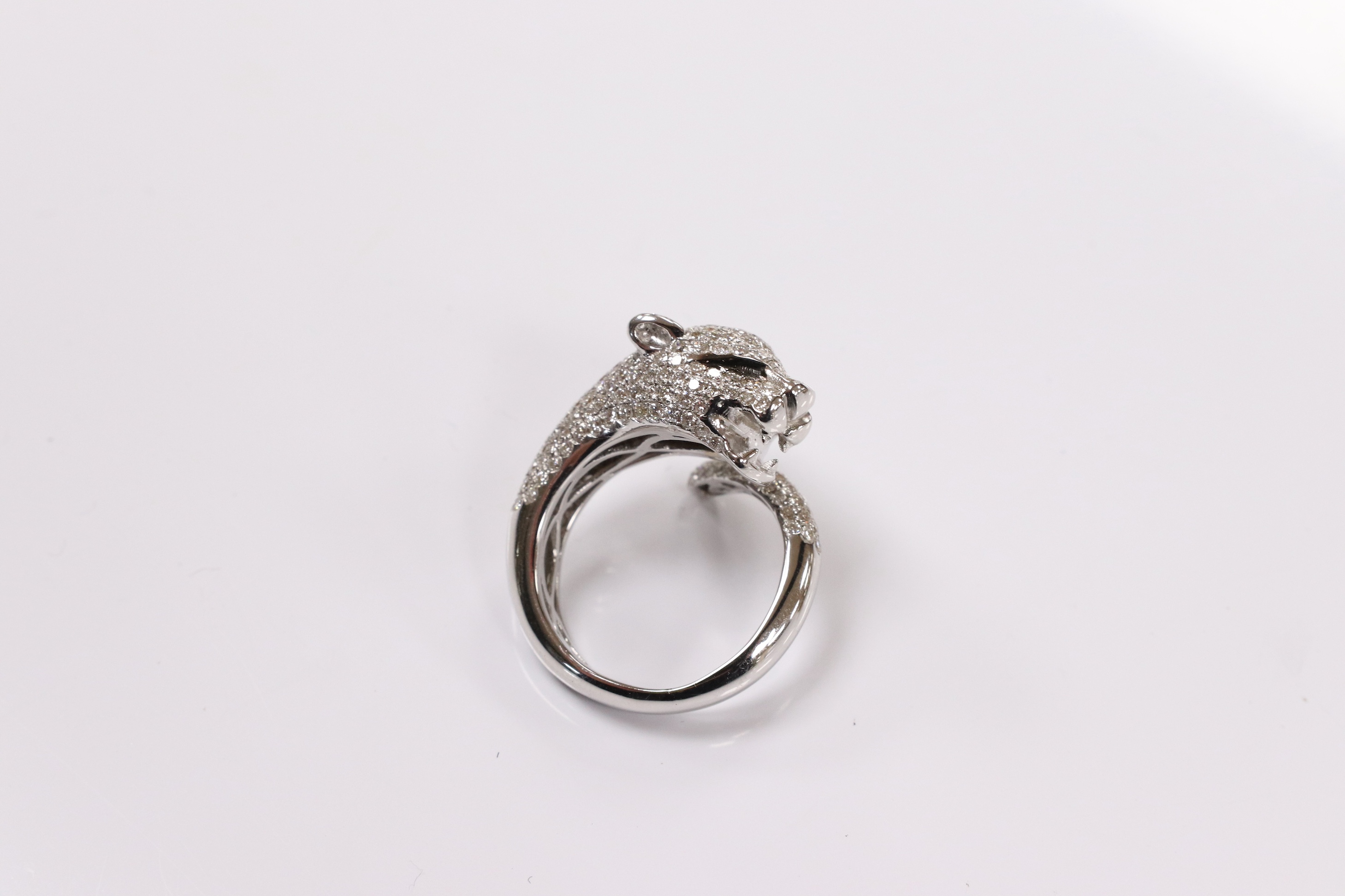 A modern Cartier style 18k white metal and pave set diamond chip dress ring, modelled as the head and tail of a leopard, size M, gross 9 grams. Condition - good